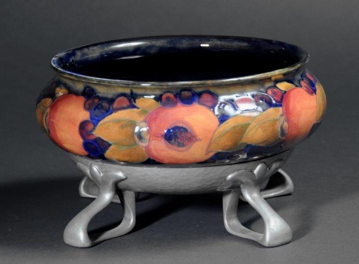 alt="Moorcroft Pomegranate range bowl on metal stand fruit and leaf decoration orange yellow green on royal blue background"