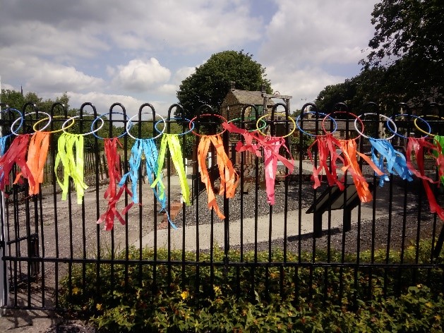 alt="chain of coulourful plastic rings and streamers advertise the dig"