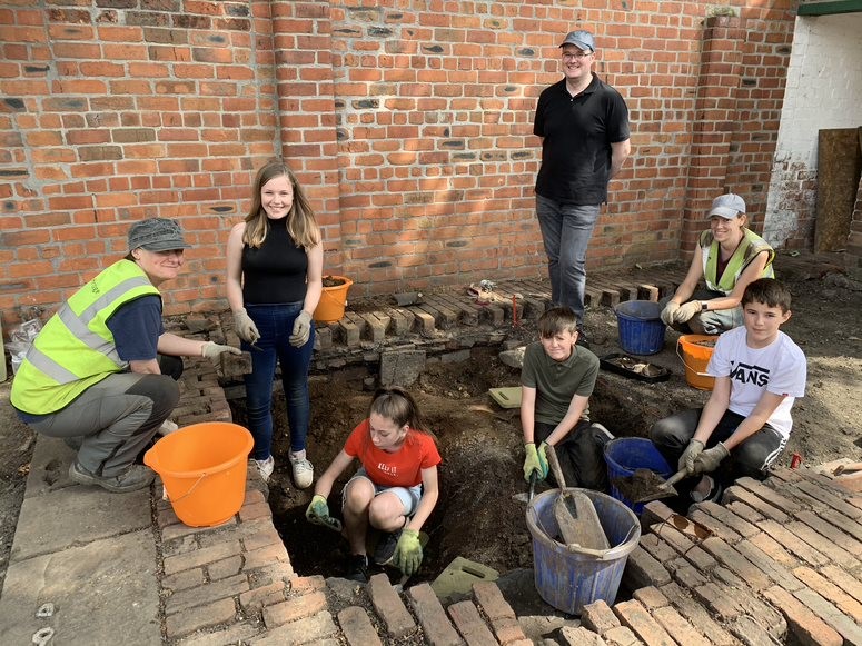 alt="students working with hand shovels and buckets trench 2"