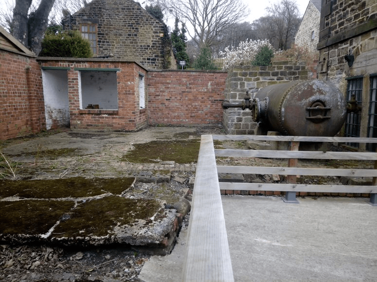 alt="yard behind engine house, showing old concrete surface covered in moss"