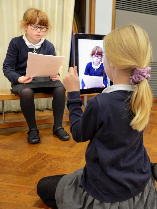 alt="two pupils using ipad to film, news report"