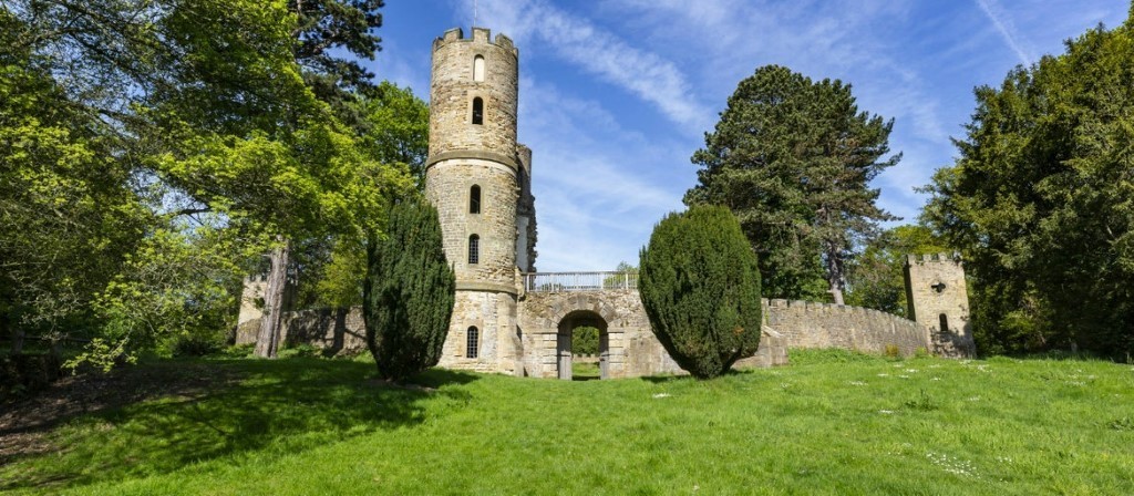 alt="Stainborough Castle, round narrow tower with curving stone wall surrounded by trees"