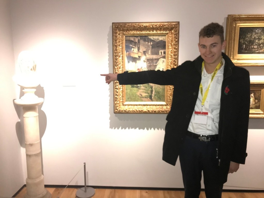 =alt"young volunteer pointing to statue in Cooper Art gallery"