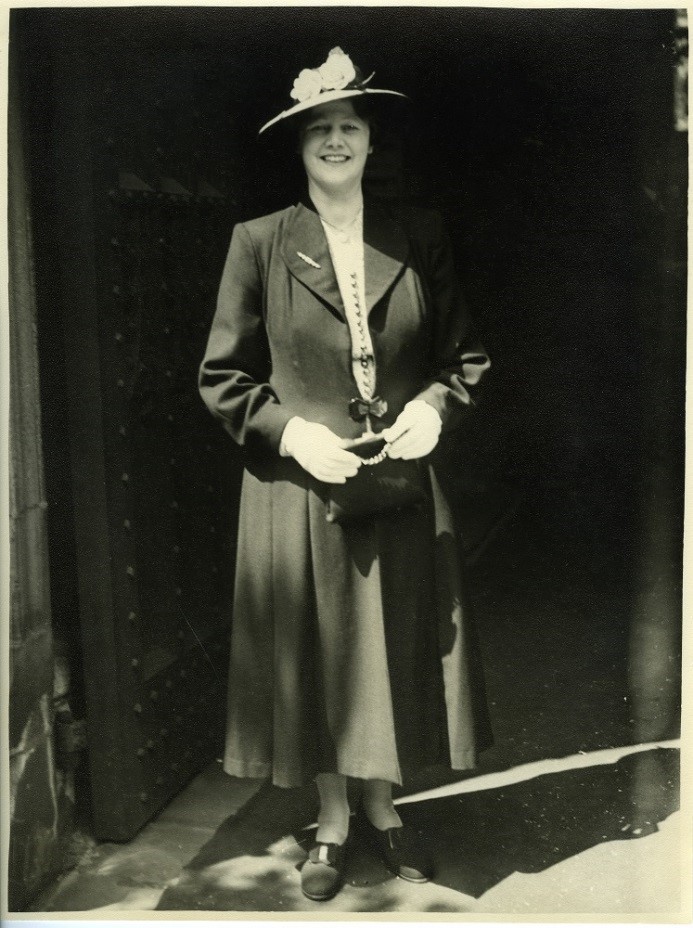alt="smiling woman in long dress and hat"