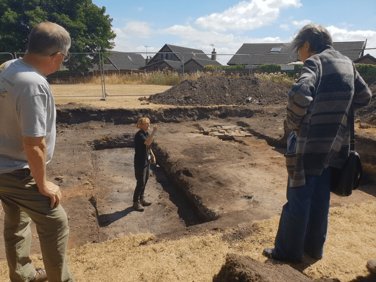 archaeologist in trench talking to members of the public