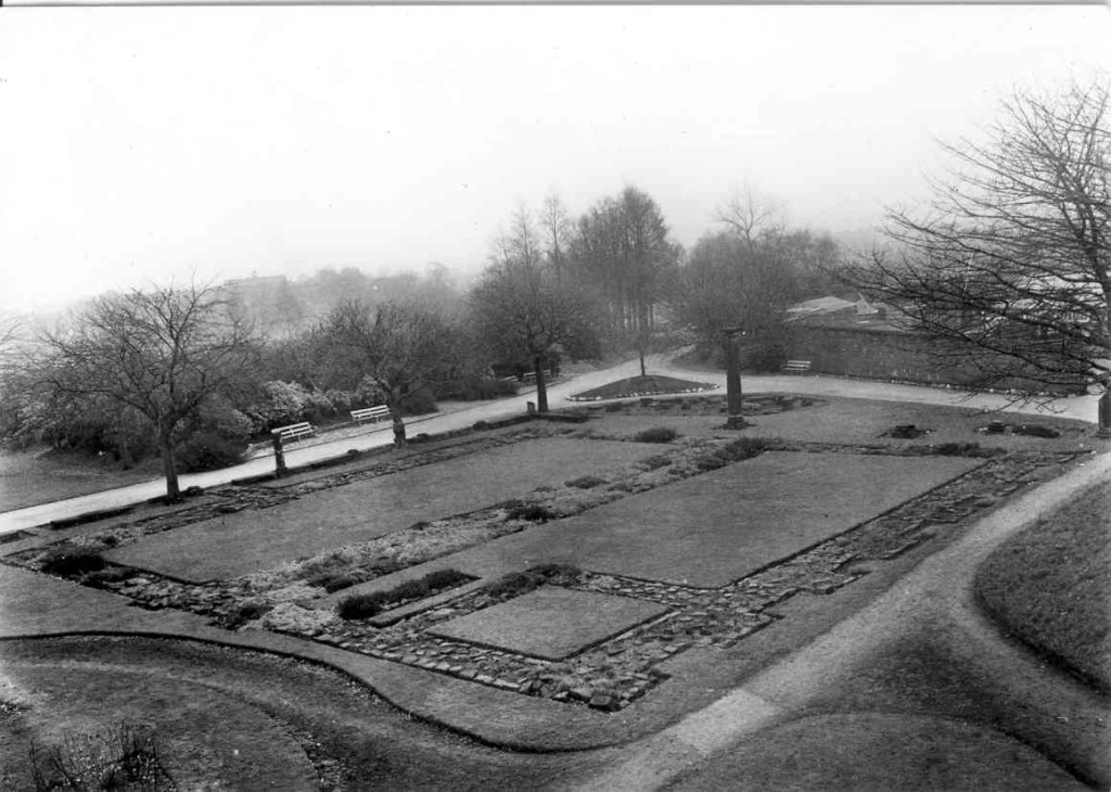 alt="foundations of rectangular building with well kept lawns and trees behind"