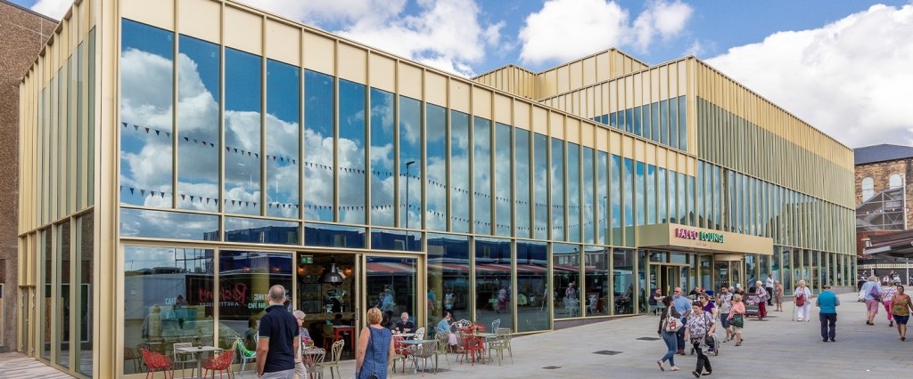 Large modern gold box-shaped building with reflective windows