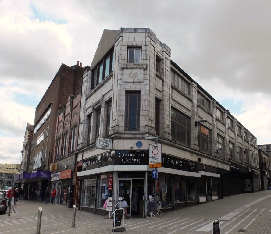 White 3 storey 1920s building with shops on ground floor