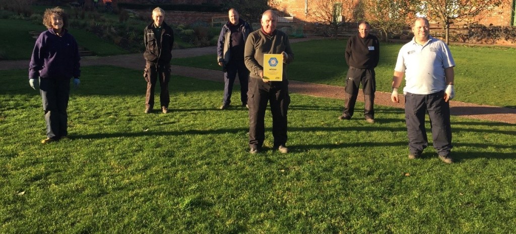 Six volunteers in a park receiving a certificate