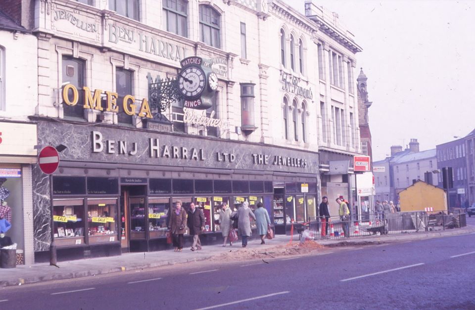 Coloured photo of the ring shop, there are people in the foreground and work appears to be done on the road.