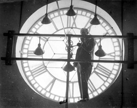 A black and white photo of of the town hall clock face with a man, engineer stood in front of it from the inside