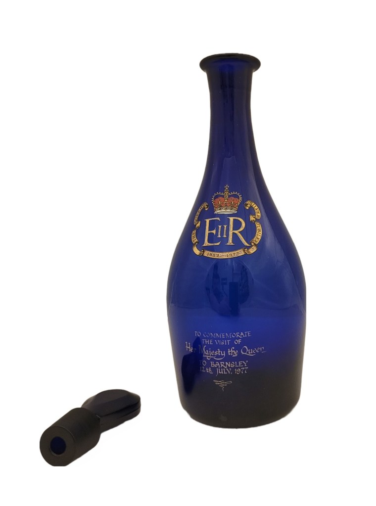 A blue decanter with the date of the Royal visit in 1977 on the front