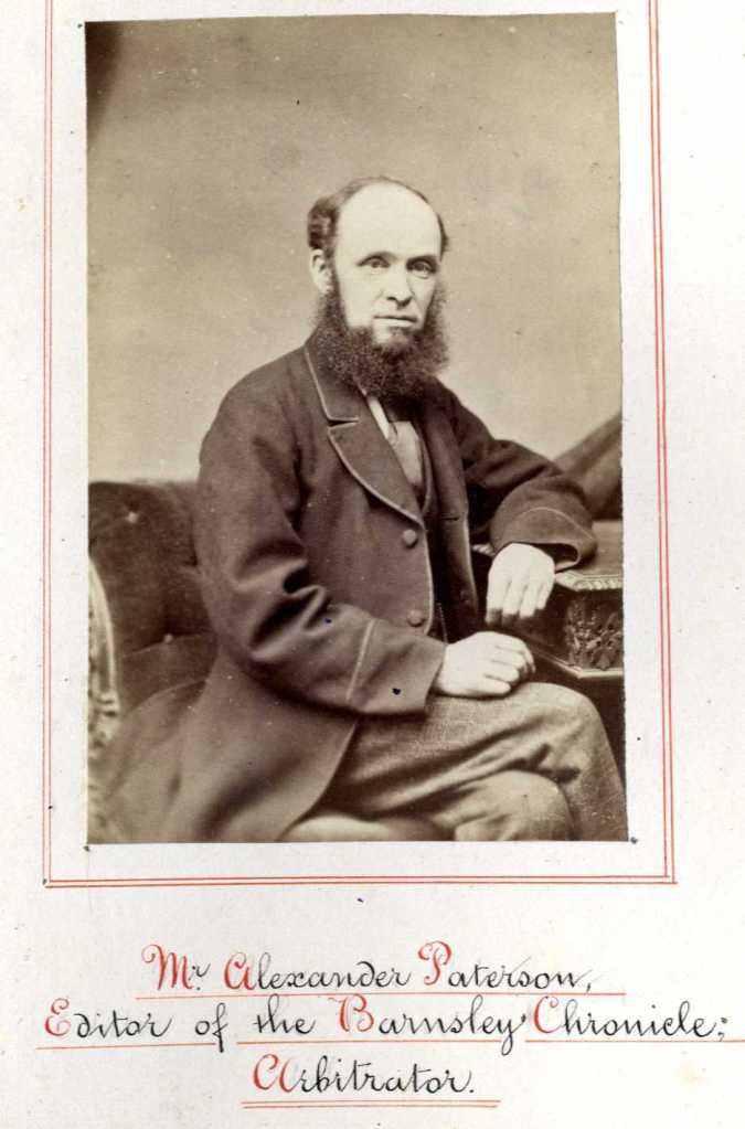 A man with a bushy beard, seated and looking towards the camera