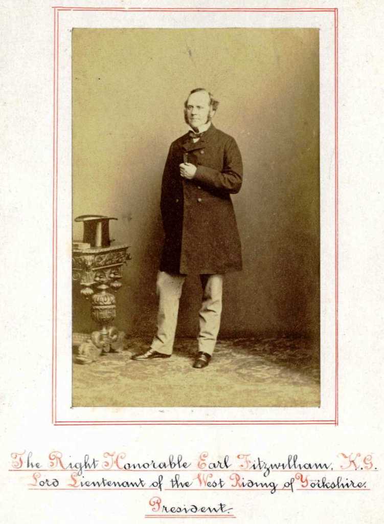 A man stood next to a small table which has a top hat rested on the top of it