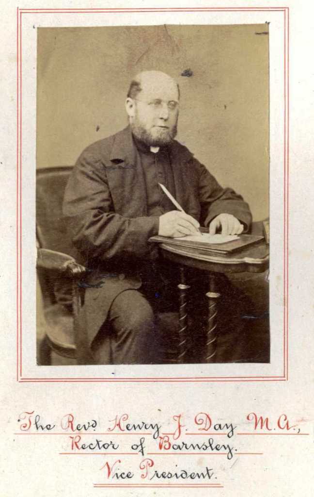 A vicar say at a small table with a writing implement in hand
