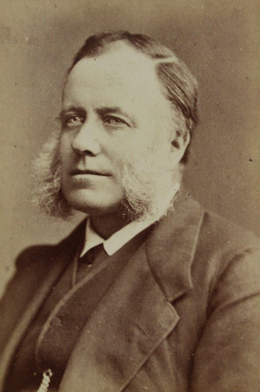 A man in a suit jacket who has very bushy and distinctive sideburns!