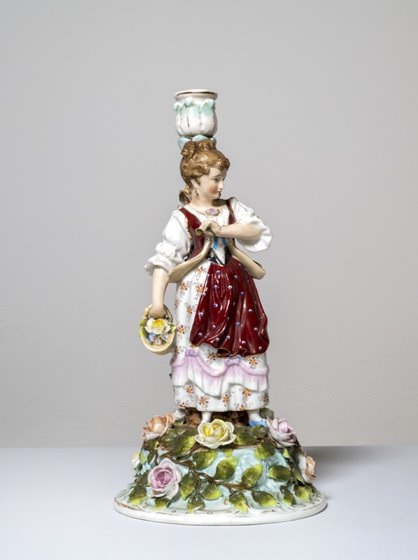 A figurine of a lady carrying a basket of flowers