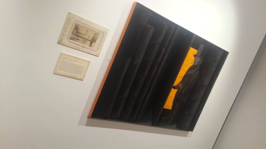 A mainly black painting next to the photo that indluenced it