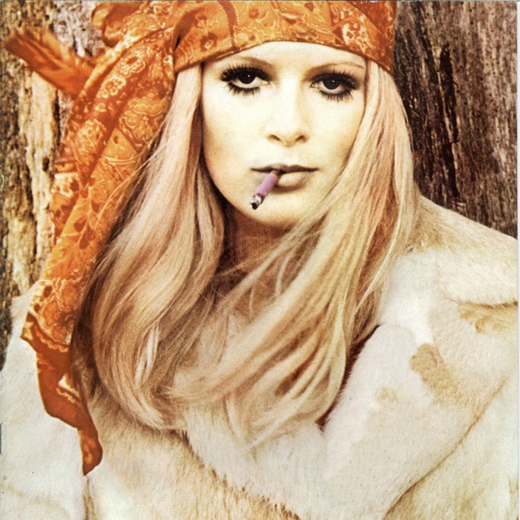 Victoria is wearing a orange head scarf and is smoking a cigarette