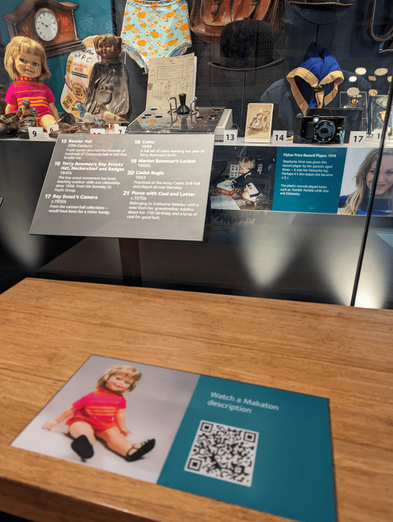 The memory box case at Experience Barnsley, in the foreground is our giggles doll next to a QR code