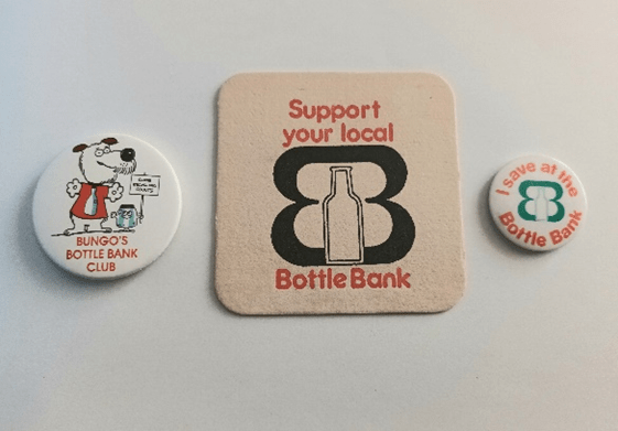 A coaster and two badges, 'support your local bottle bank' one of the badges has a picture of a dog with 'Bungo's Bottle Bank'