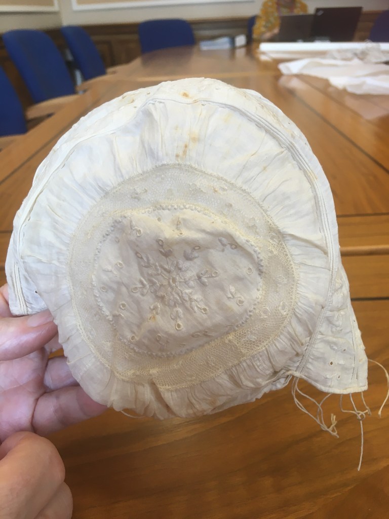 The back of an early baby’s bonnet, slightly faded in areas 