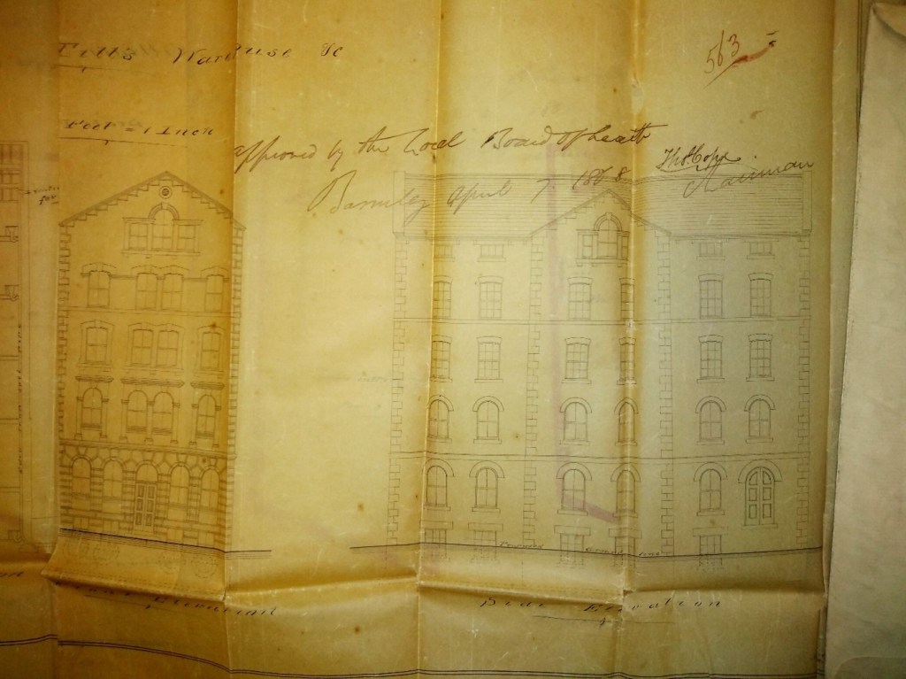 Architects drawing of the main elevations of 58 Eldon Street. A heading at the top of the document says 'Till's Warehouse' A handwritten note across the drawing indicates that it was approved. The elevations look much as they do today, with the exception of the ground floor, which has a central doorway and tall round-headed windows facing Eldon Street, and a series of similar round-headed windows and a loading in door on the ground floor at the side/rear of the property.