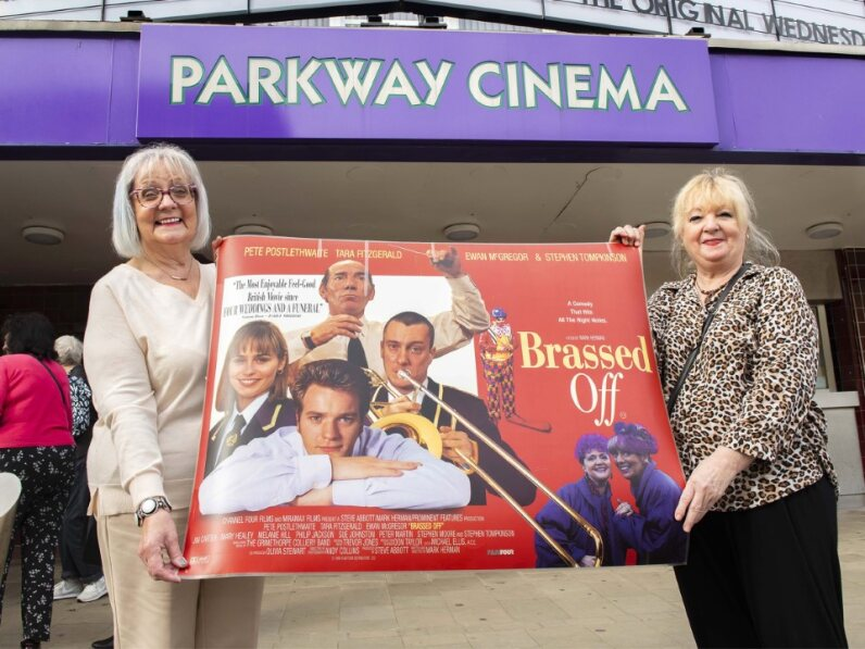 Two people holding a Brassed Off poster.