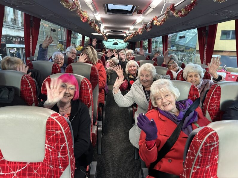 Lots of people on a bus waving to the camera