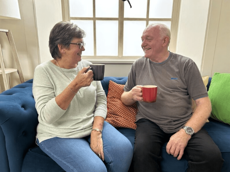 Two people on a sofa holding mugs