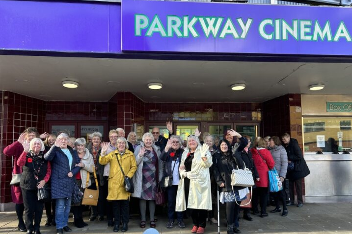 A group of people, mainly female waving to the camera outside Parkway Cinema