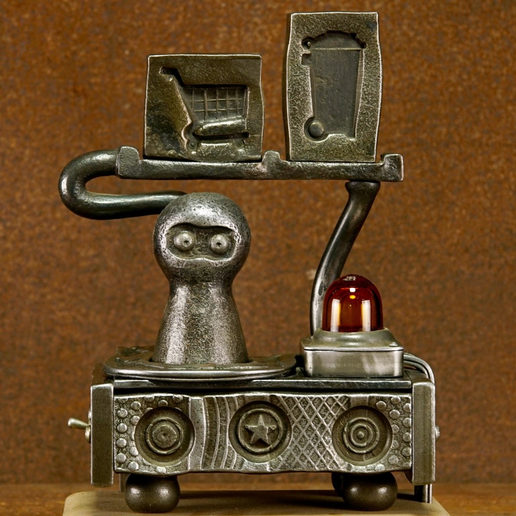 A whimsical metal sculpture features a round-headed figure, a shopping cart icon, and a trash can icon. The sculpture includes a red light, gears, and intricate patterns on a brown textured background.
