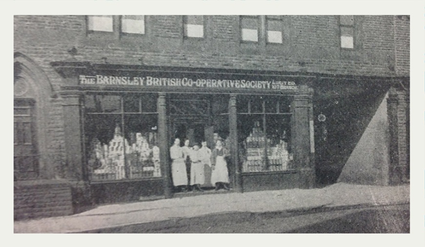 Historic photograph of the Barnsley British Co-Operative Society storefront, featuring several individuals in front of the shop.