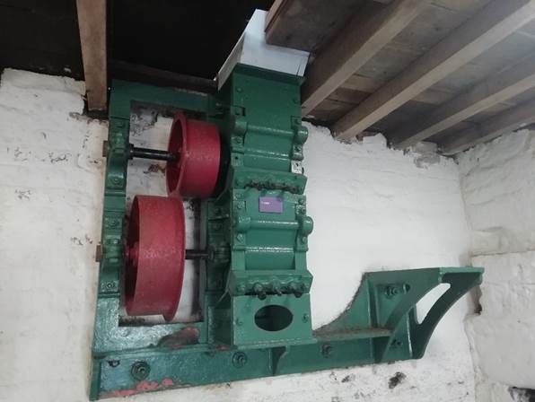 Close-up of a green and red mechanical device mounted on a wall, likely part of milling machinery at Worsbrough Mill.