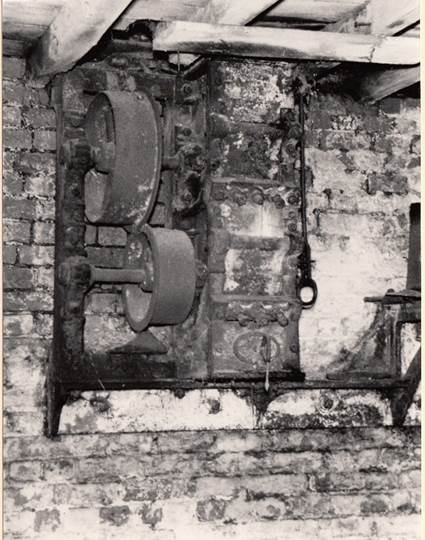 Antique machinery with pulleys mounted on a brick wall, indicative of milling equipment from the historical Worsbrough Mill.