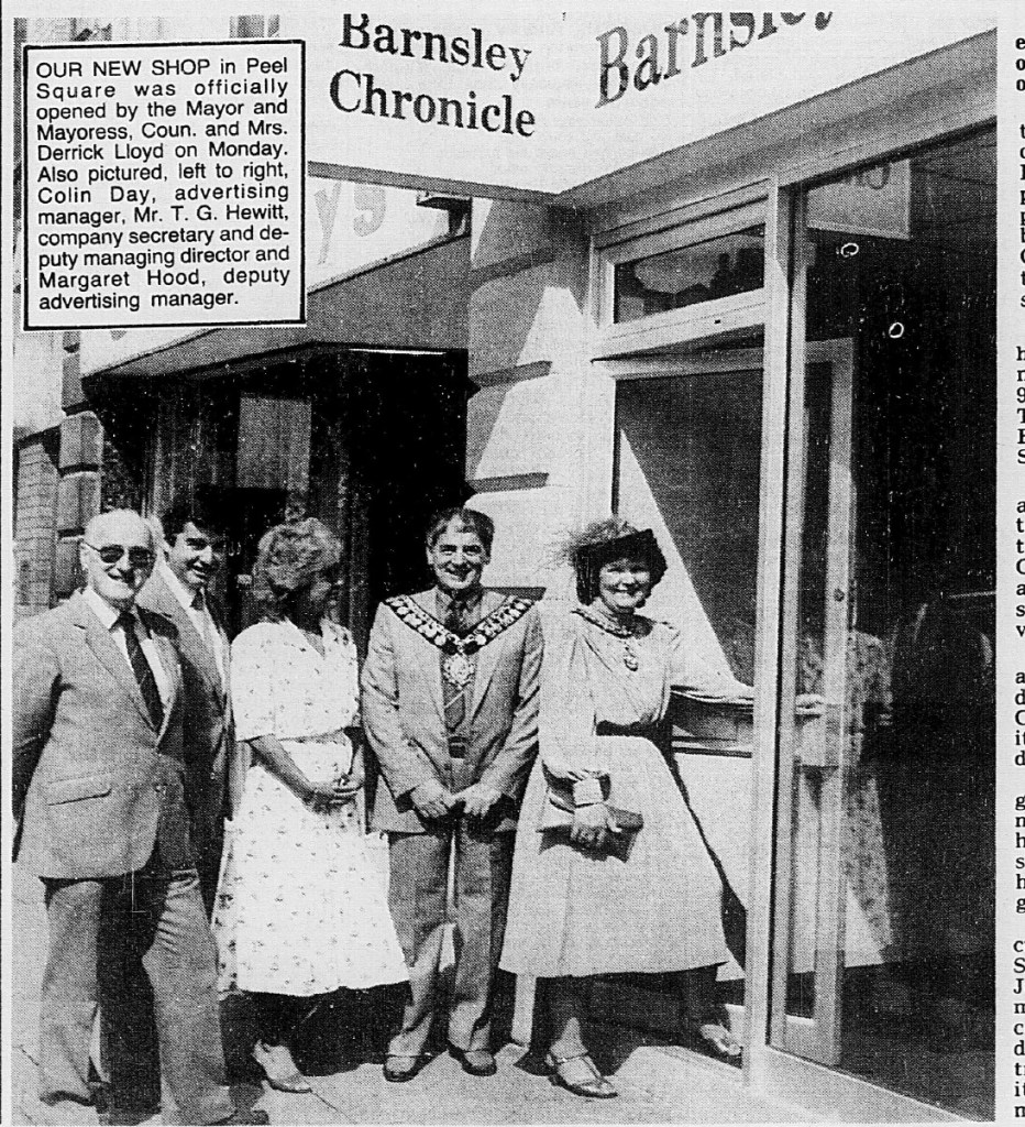 A historic photo featuring the opening of a new Barnsley Chronicle shop in Peel Square, with Mayor Derrick Lloyd and several other individuals posing outside.