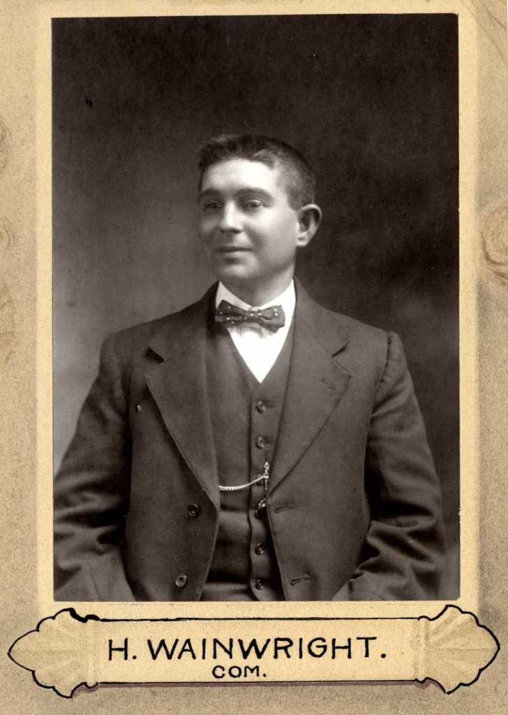 Portrait of H. Wainwright, dressed in a formal suit with a bow tie, featured in an early 20th-century photographic studio setting.