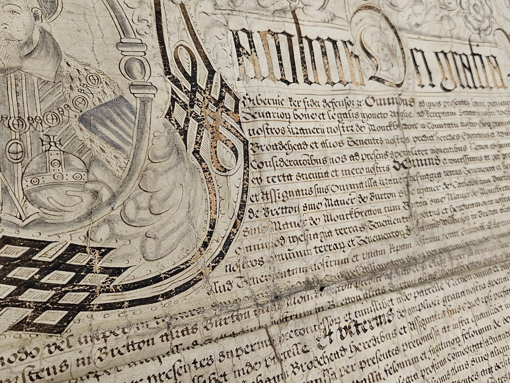Close-up of an ornate parchment document featuring intricate lettering and a portrait of King James I, highlighting its historical significance.