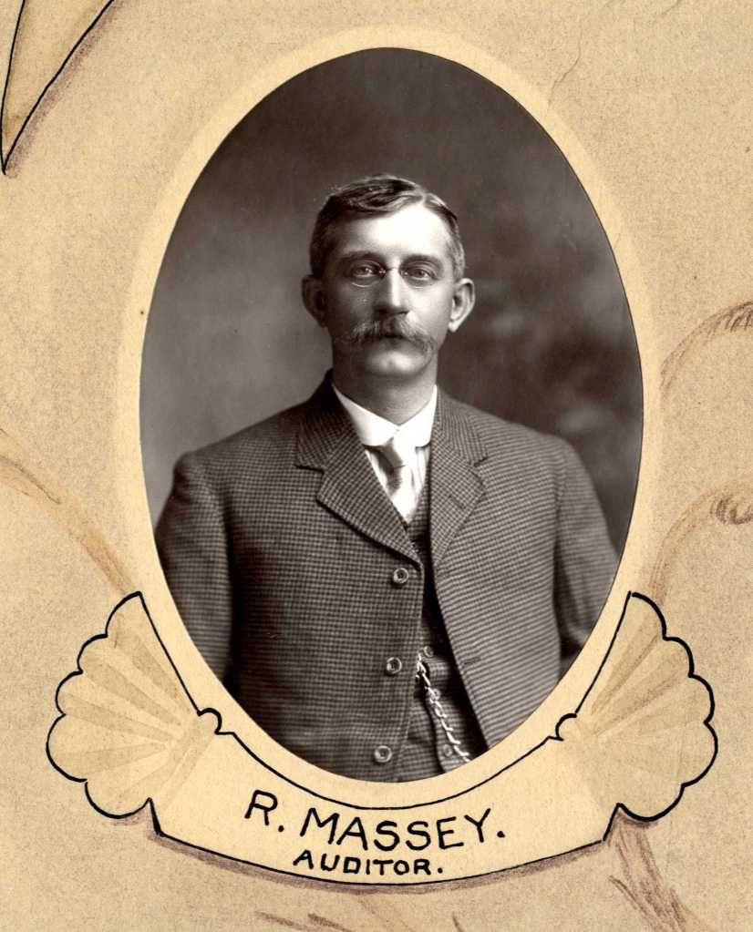 Black and white portrait of R. Massey, an auditor, wearing a suit and glasses, framed within an ornate border.