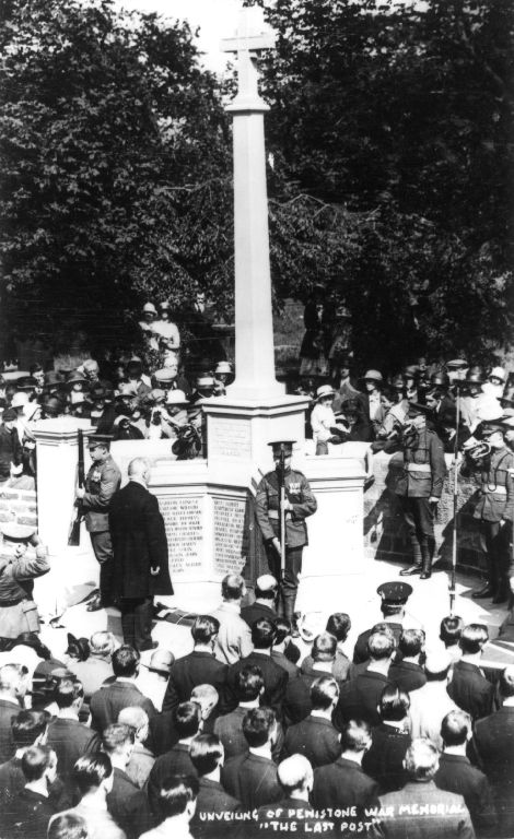 A historic black and white photograph of a large crowd gathered for the unveiling of the Penistone War Memorial, featuring a prominent stone cross and military personnel in attendance.