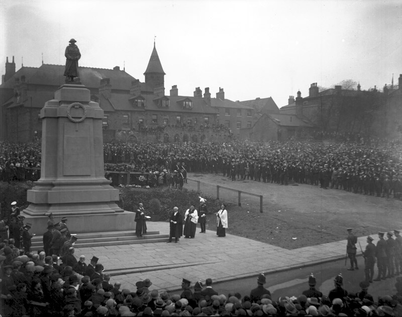 Historic photo of the unveiling ceremony of Barnsley's war memorial in 1925, showing a large crowd gathered around the monument with officials and clergy present.