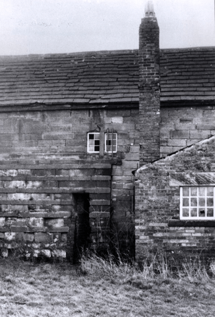 Historic view of a stone building with a chimney and windows, part of Worsbrough Mill, showcasing the architecture and condition of the structure.