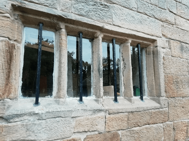A stone window with metal bars, part of the historical Worsbrough Mill, showcasing its architecture and heritage.